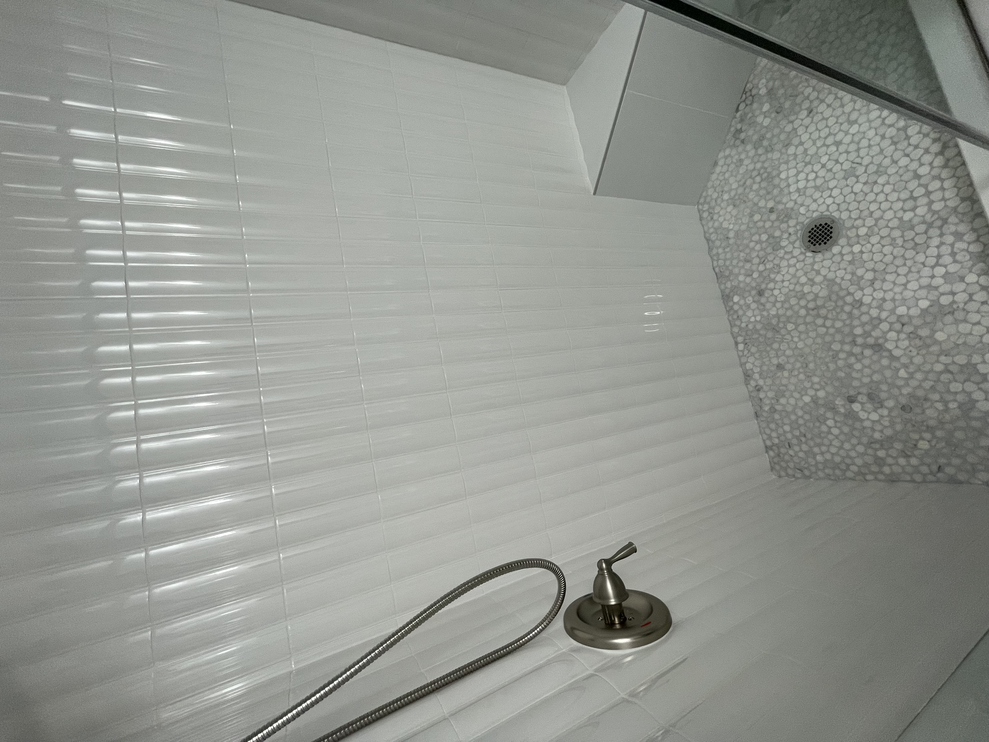 Guest bathroom shower with ribbed white subway tile and pebble mosaic floor, Tampa Bay FL
